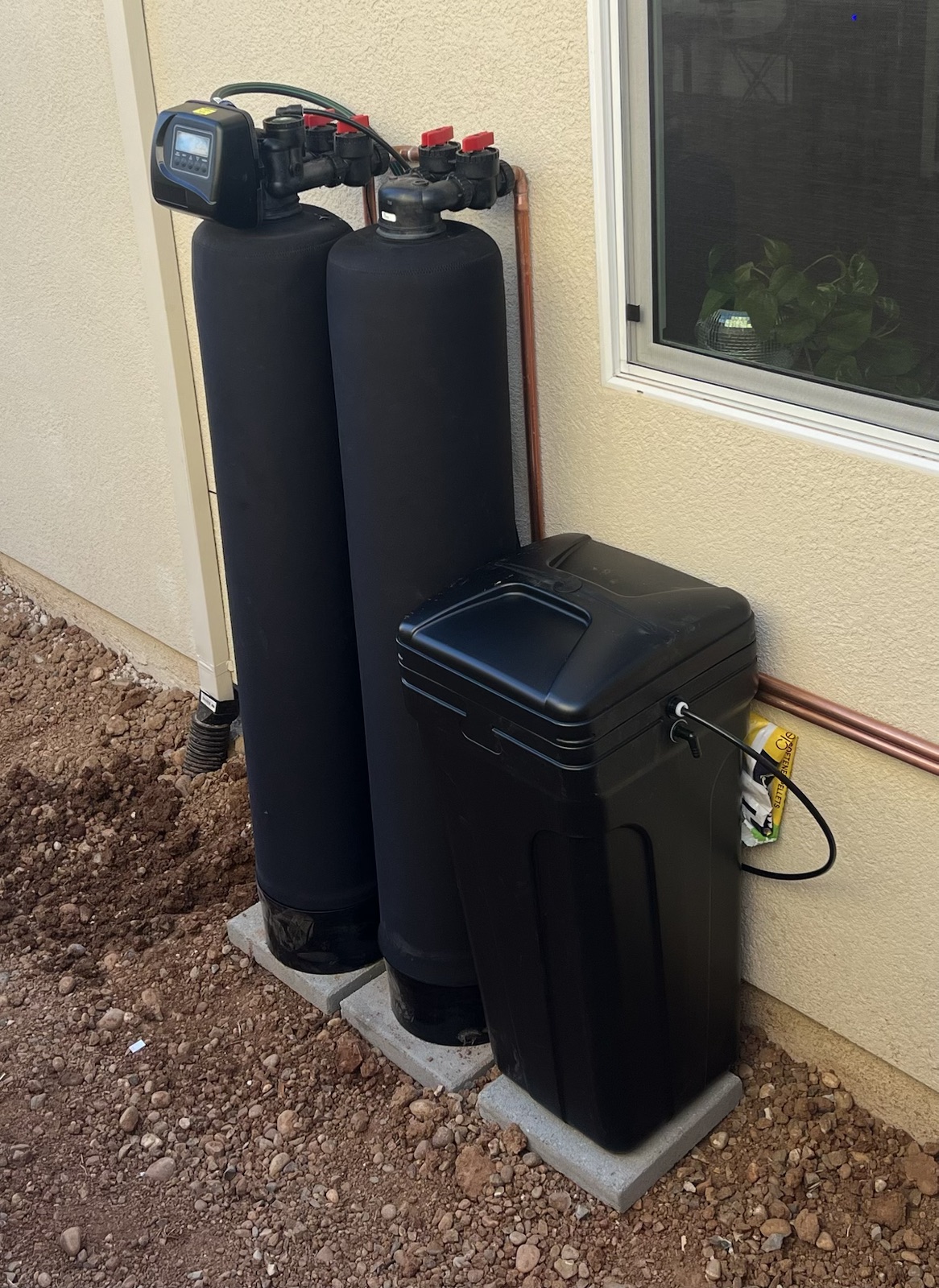 Dual-tank whole-home filtration and softening equipment installed along an exterior wall at a Rancho Cordova home